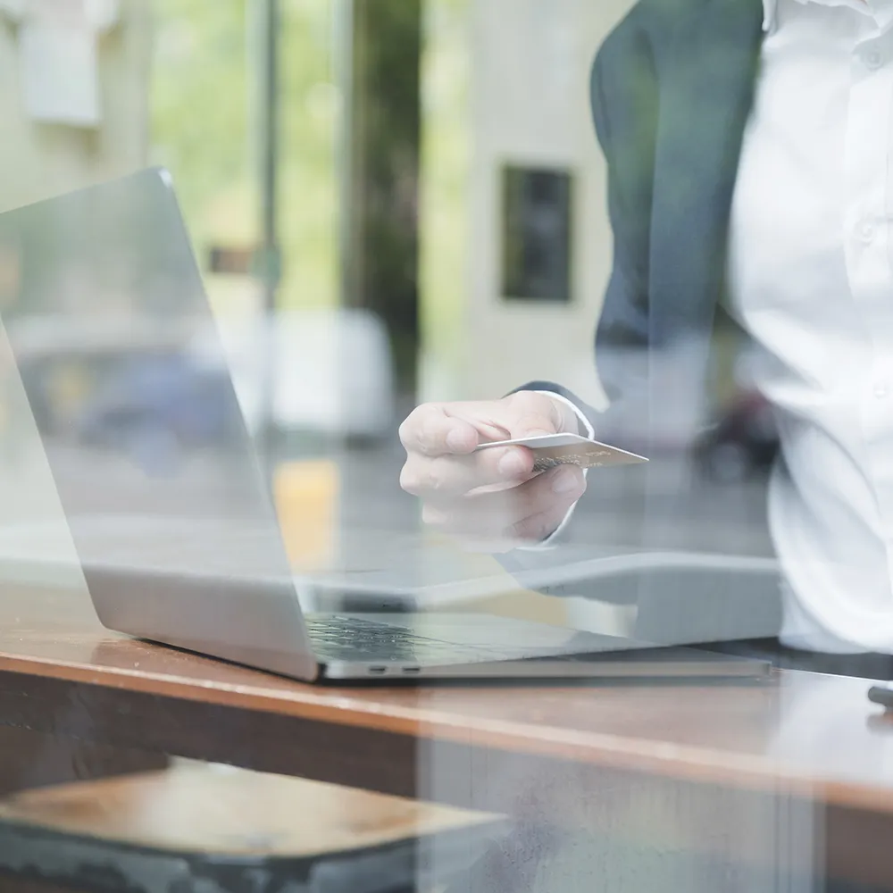 Photo d'un homme avec une carte bancaire devant un pc
