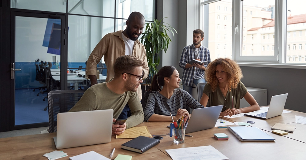 Groupe de collègues travaillant ensemble autour d’un bureau.